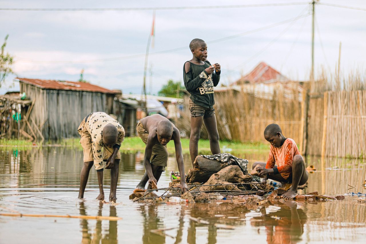hero-img-01 A group of children playing in a flooded rural village stream.