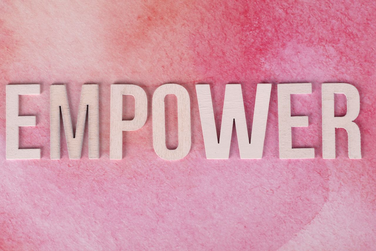 gallery-1 Wooden letters spelling 'EMPOWER' on a pink watercolor background.
