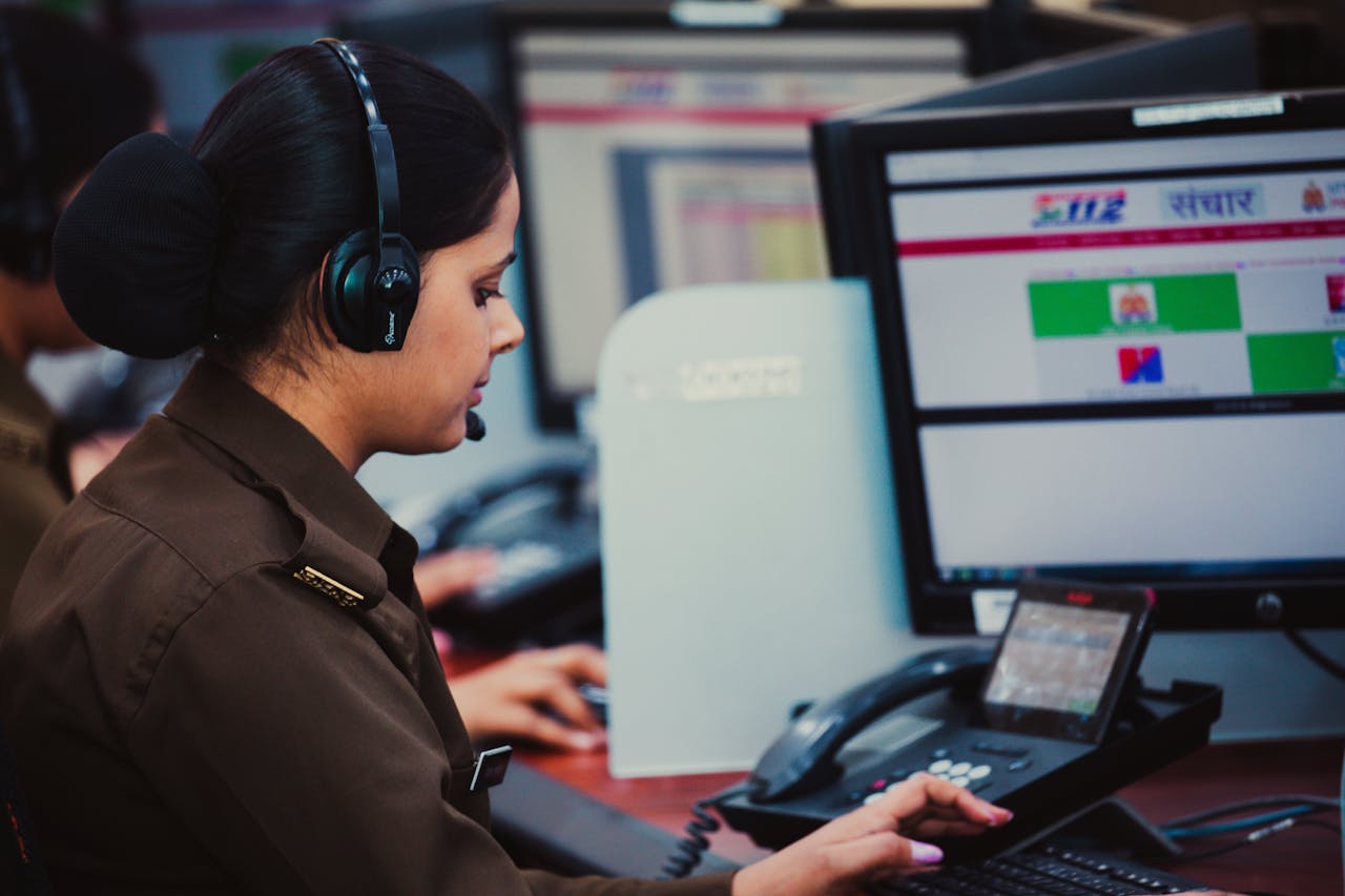services-02 Focused call center dispatcher in uniform using computer and headset in office environment.